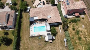 Eine Vogelperspektive eines Wohngebiets mit einem Swimmingpool, umgeben von einer Terrasse, einer überdachten Veranda und einer kleinen Grünfläche.