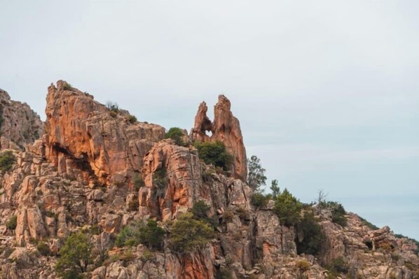 Un paisaje montañoso agreste con formaciones rocosas destacadas y vegetación escasa.