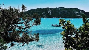 A coastal view with clear turquoise water, boats, and a mountainous backdrop. - Chalet Zen (Peri)
