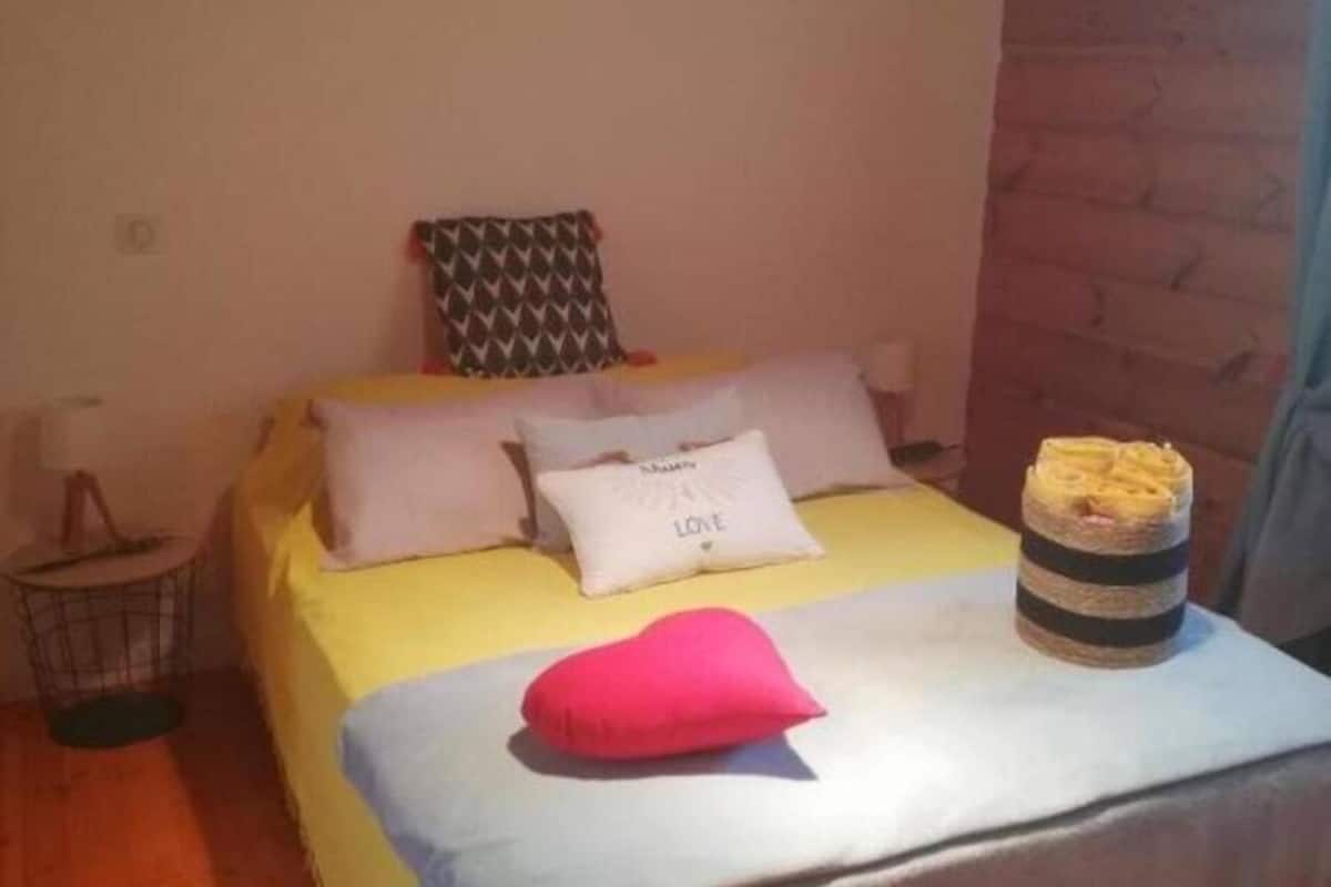 A bedroom with a bed, pillows, a bedside lamp, and a wooden floor.