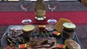 Ein Tisch ist gedeckt mit einer Weinflasche, zwei Gläsern und einer Auswahl an Käse und Fleisch.