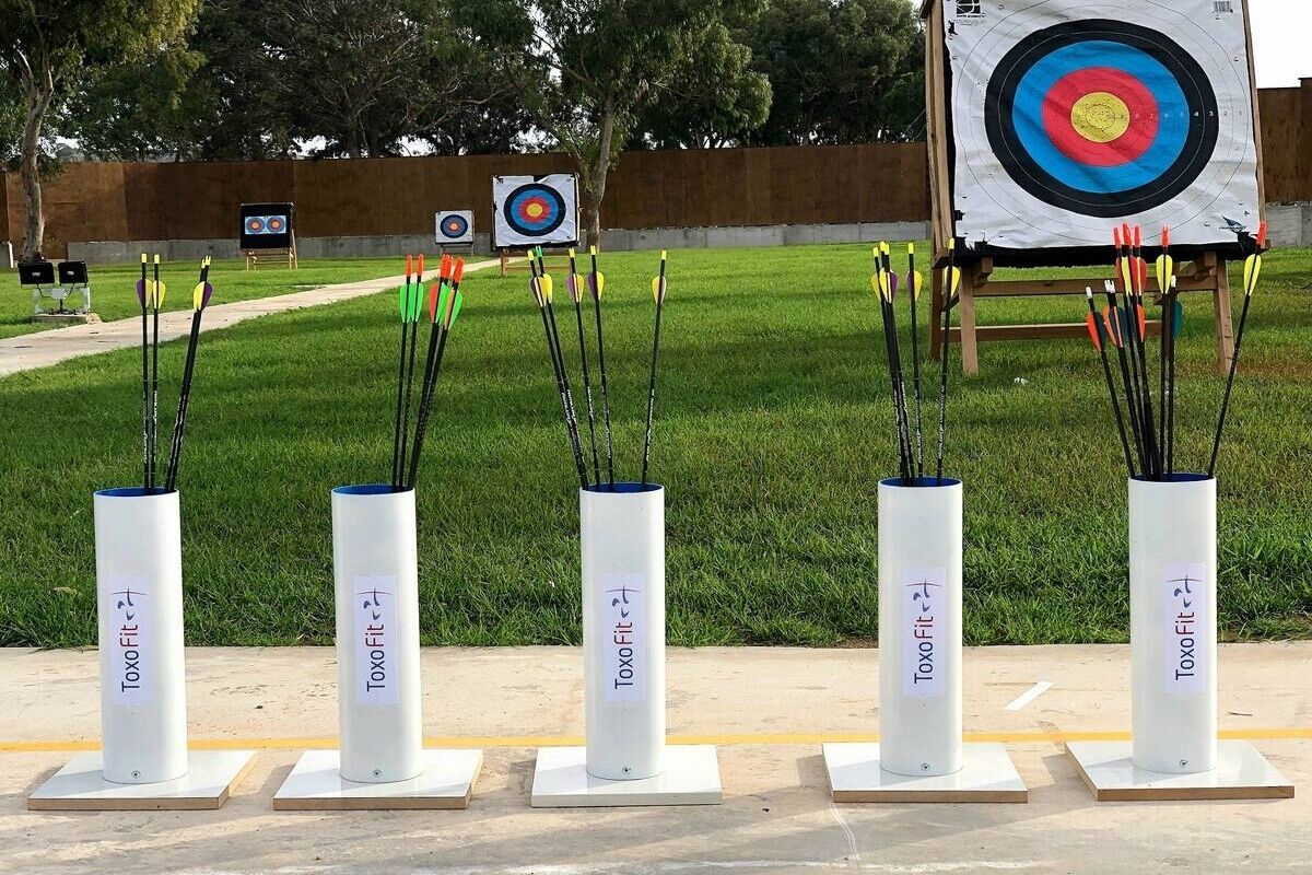 An archery range with multiple targets and arrows set up for practice.