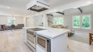 Une cuisine moderne dotée d’un îlot central, de fours encastrés et d’un coin repas avec une banquette et des chaises.