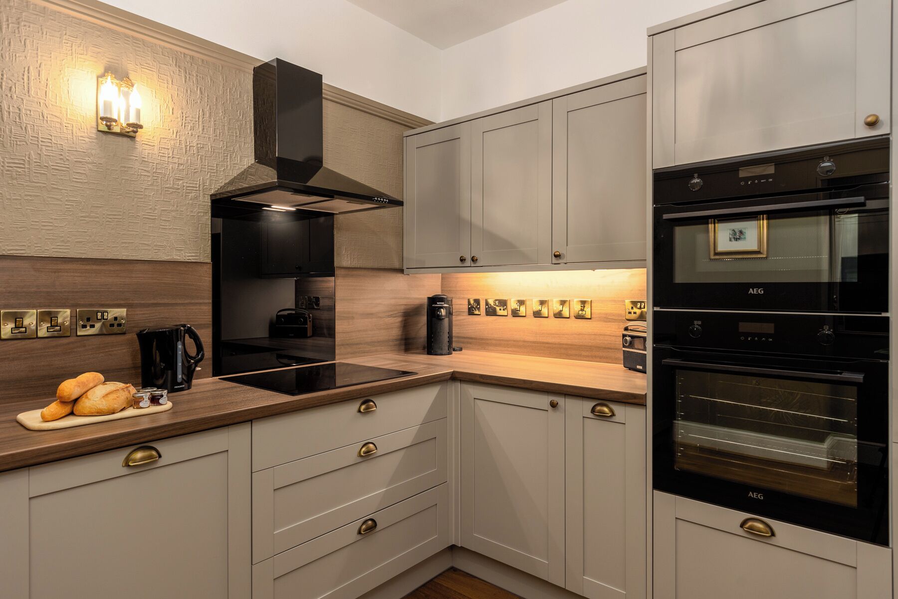 A modern kitchen with a built-in oven, a coffee machine, and a bread display.