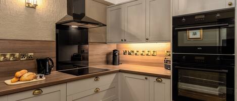 A modern kitchen with a built-in oven, a coffee machine, and a bread display.