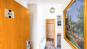 A hallway with a wooden door labeled '61', a radiator, and a painting of a garden. - Modern Apartment - AC- 1br-2p- Geneva (Geneva)