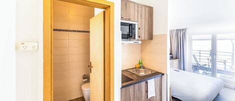 Una habitación compacta con puerta de madera que da a un baño, una kitchenette con microondas y una cama con vistas.