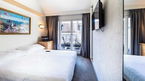 A hotel room with a large bed, a TV mounted on the wall, a painting on the wall, and a balcony with chairs. - Modern Apartment - AC- 1br-2p- Geneva (Geneva)