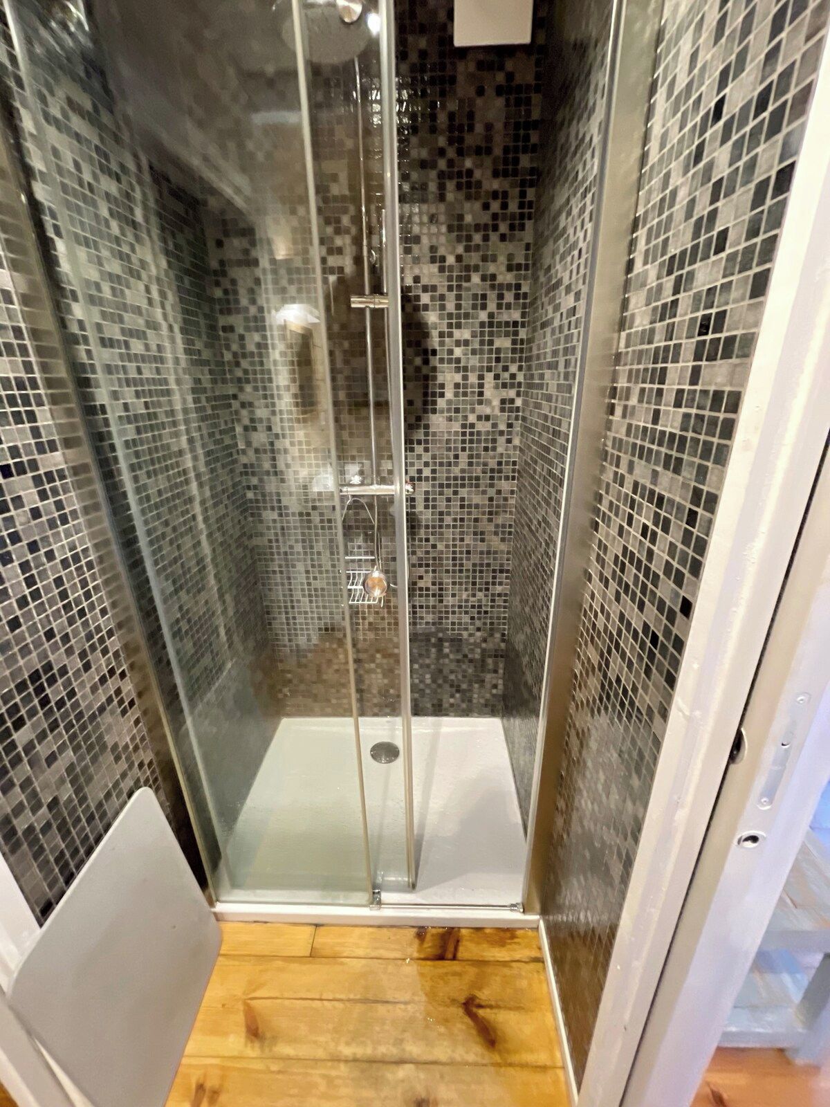 En bruseniche med glasdør og vægge af mosaikfliser.