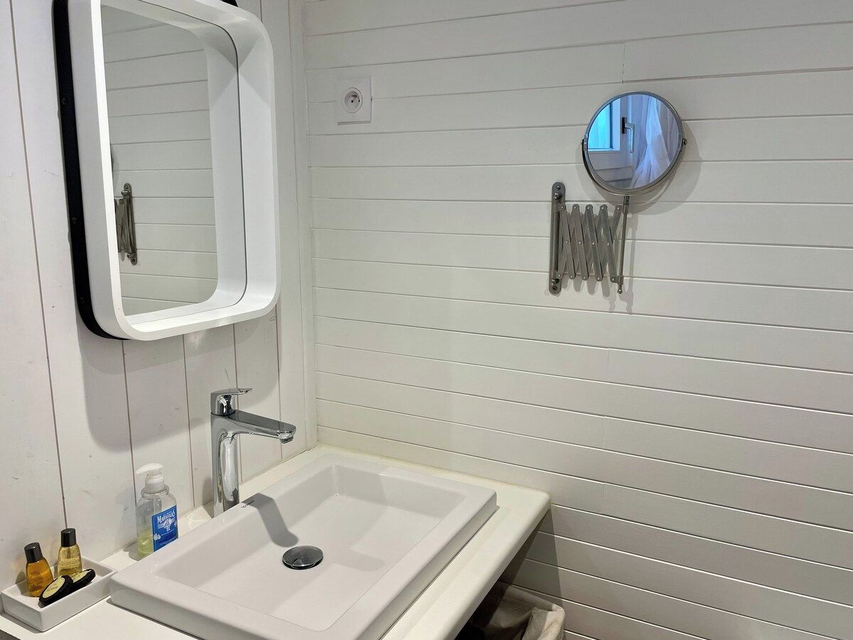 A bathroom with a white sink, a mirror, and a round mirror on the wall.
