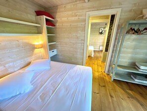 A wooden interior with a bed, a shelf with red pillows, and a door leading to another room. - Villa with pool + fantastic terraces A3699 (Lège-Cap-Ferret)