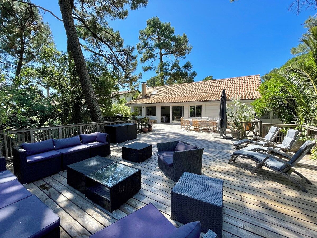 An outdoor deck with furniture, a building in the background, and surrounding trees.