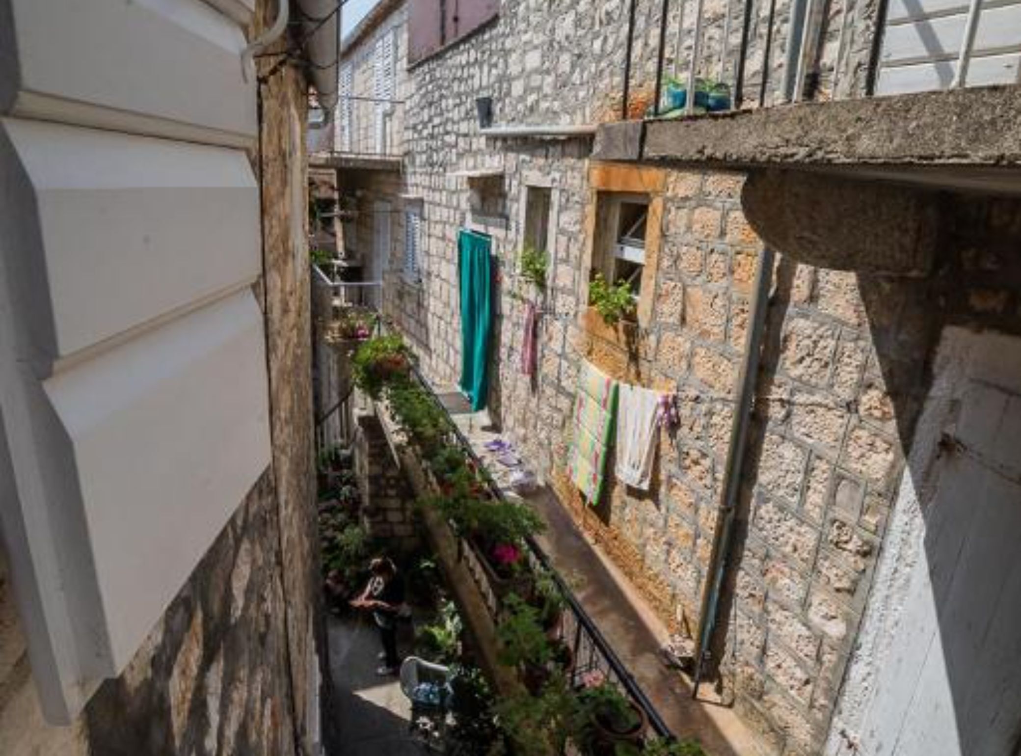 Ein schmales Steinhaus mit einem kleinen Balkon und einem Fenster mit einem grünen Vorhang.