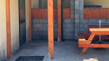 A covered outdoor area with a stone wall, wooden pillars, and a picnic table.