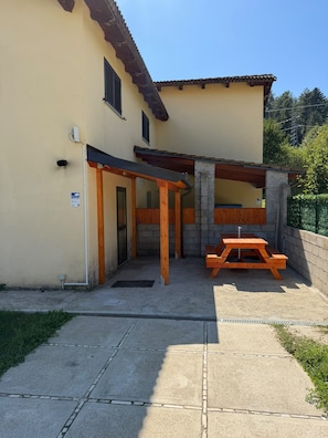 A building with a patio area, a wooden table, and a covered seating area.