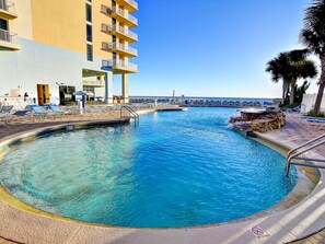 A swimming pool with lounge chairs and a building with balconies in the background. - Majestic Beach Towers I #1505 by Resort Collection (Panama City Beach)