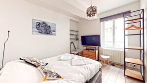 A modern bedroom with a bed, a TV, a shelf, and a window. - TIGER ROOM - Studio Gailleton Place Bellecour (Lyon)