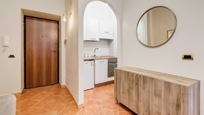 Une cuisine avec des meubles blancs, une porte en bois et un miroir rond accroché au mur.