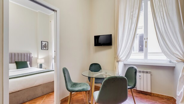 Une chambre à coucher comprenant un lit, une table de chevet, un miroir et un téléviseur fixé au mur.