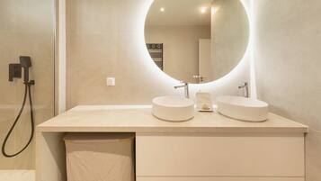 A modern bathroom with two round sinks, a large mirror, and a towel rack.