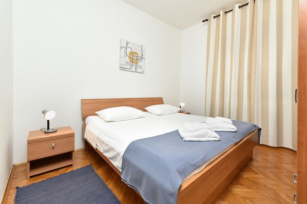 A neatly made bed with a blue blanket, a bedside table with a lamp, and a wall-mounted artwork. - Comfortable Stay in Fažana With Outdoor Space (Fazana)