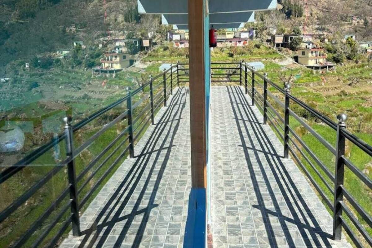 Eine Treppe führt zu einer Terrasse mit Blick auf ein Tal und Gebäude.