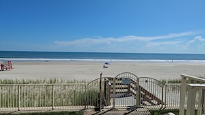 A beach view with a wooden deck, a lifeguard stand, and a sign indicating no sand in the pool.