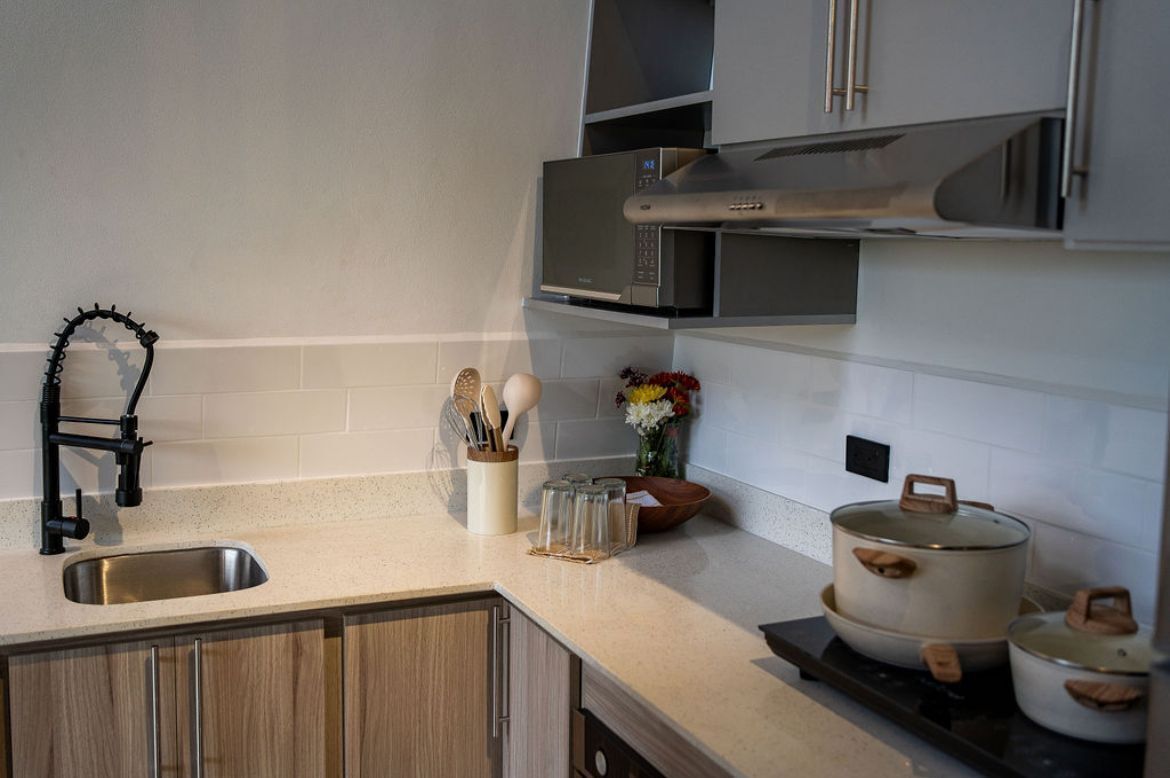 A kitchen with a stainless steel sink, a microwave, and wooden cabinets.