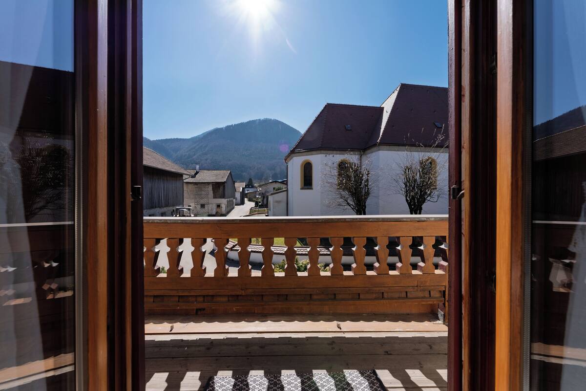 Een houten balkon met uitzicht op een berg en gebouwen.