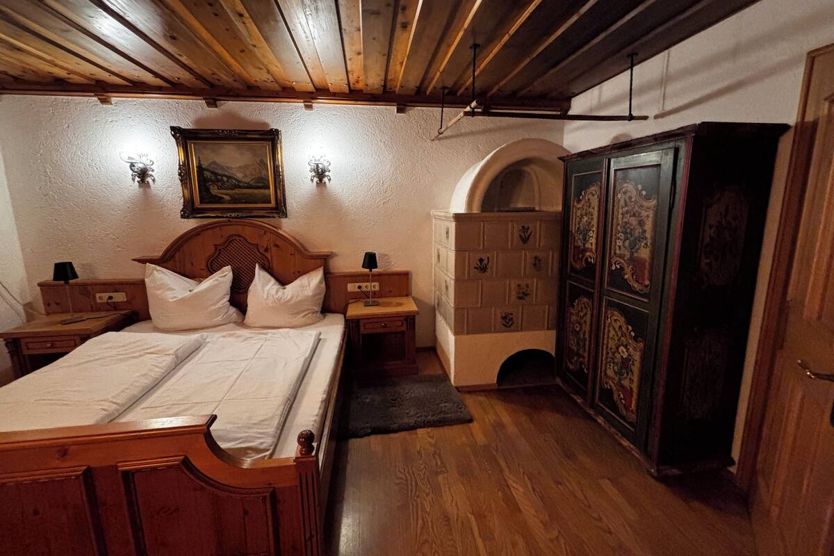 Een slaapkamer met een houten bed, nachtkastjes, een dressoir en een kledingkast.