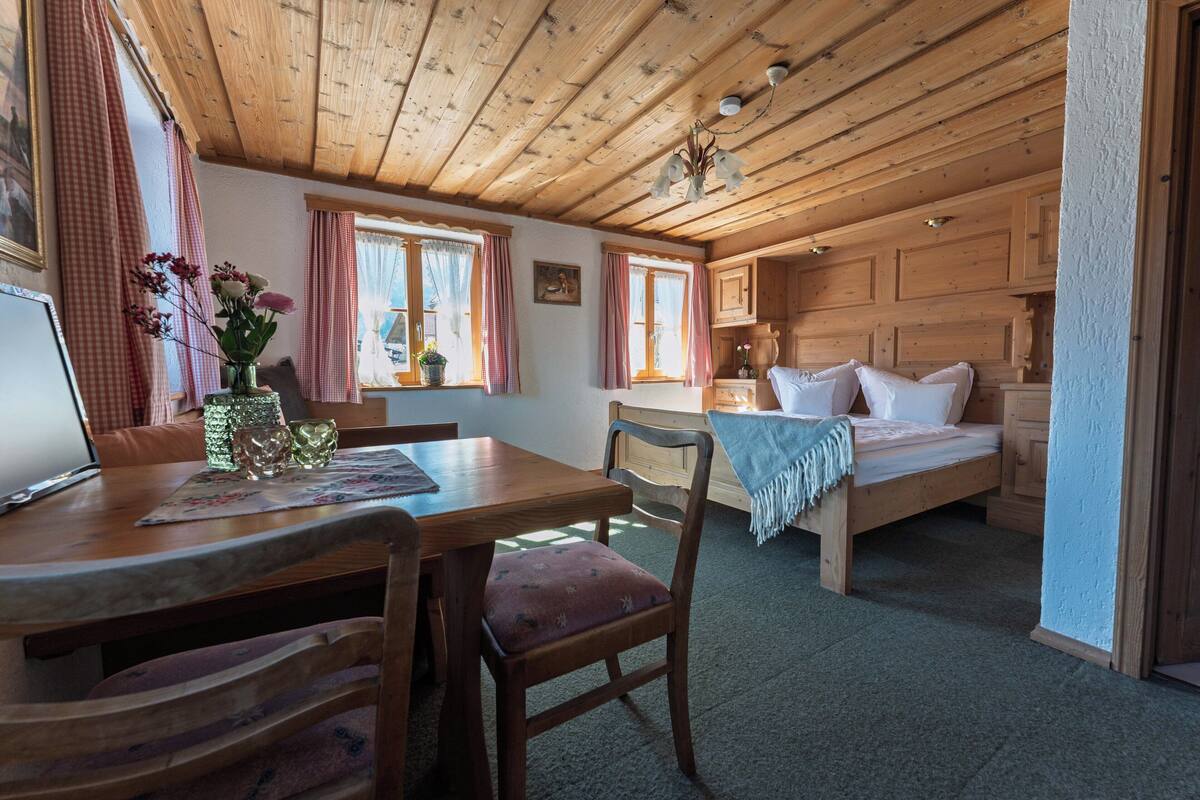 Een gezellig houten blokhut met een eethoek, een bed en een keuken.