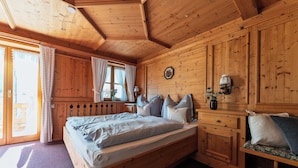A wooden bedroom with a bed, a dresser, and a bench.