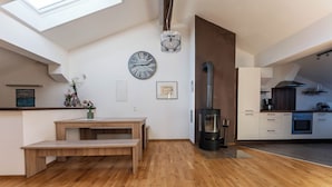 A modern kitchen with a wooden bench, a large clock, and a wood-burning stove.