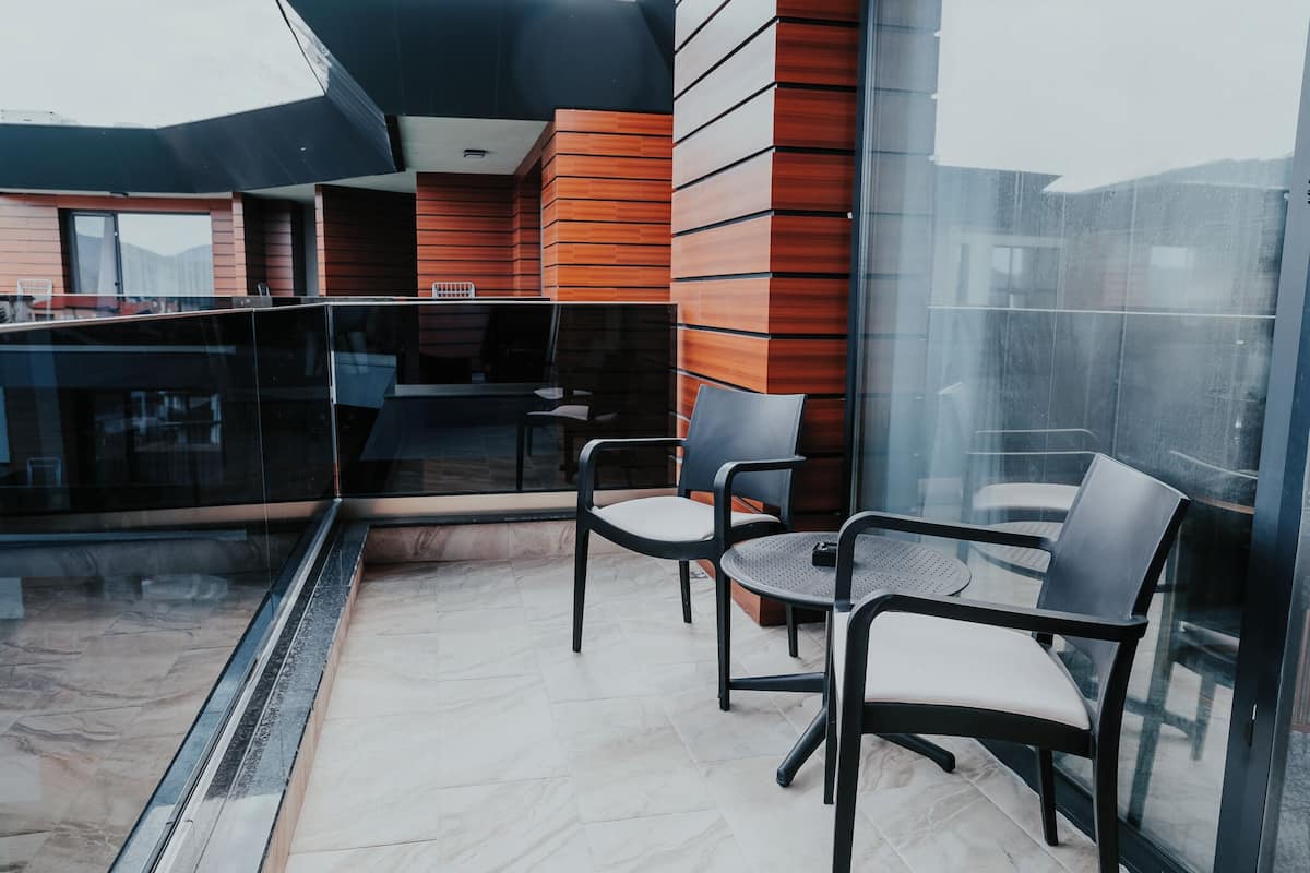 A modern outdoor seating area with glass railings, a table, and chairs.