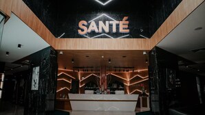 A modern reception area with a prominent 'SANTÉ' sign, wooden accents, and a marble reception desk. - Sante SPA Hotel (Velingrad)