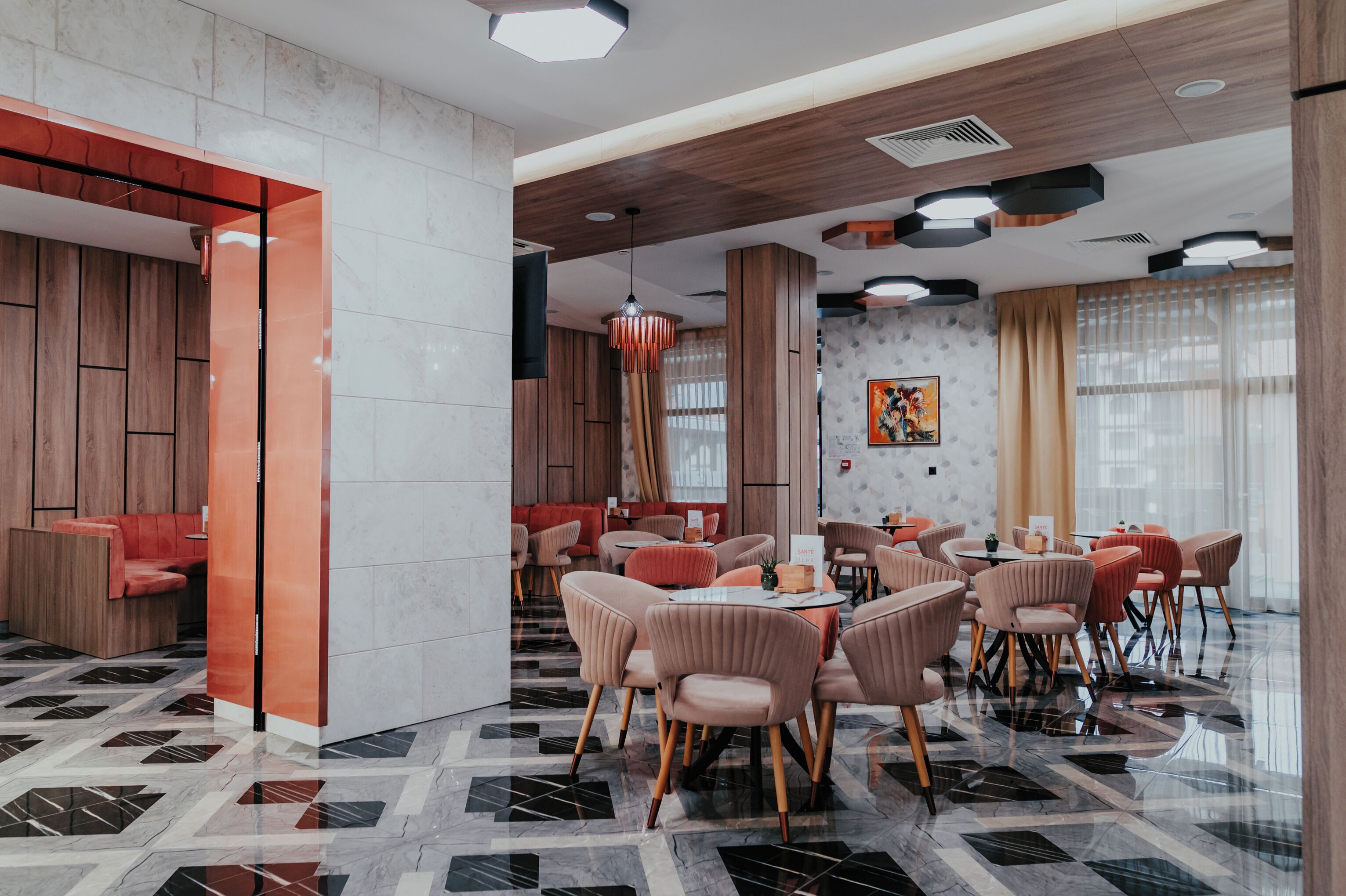 Un comedor moderno con variedad de opciones de asientos, incluyendo mesas redondas y sillas acolchadas, y un suelo con diseño.
