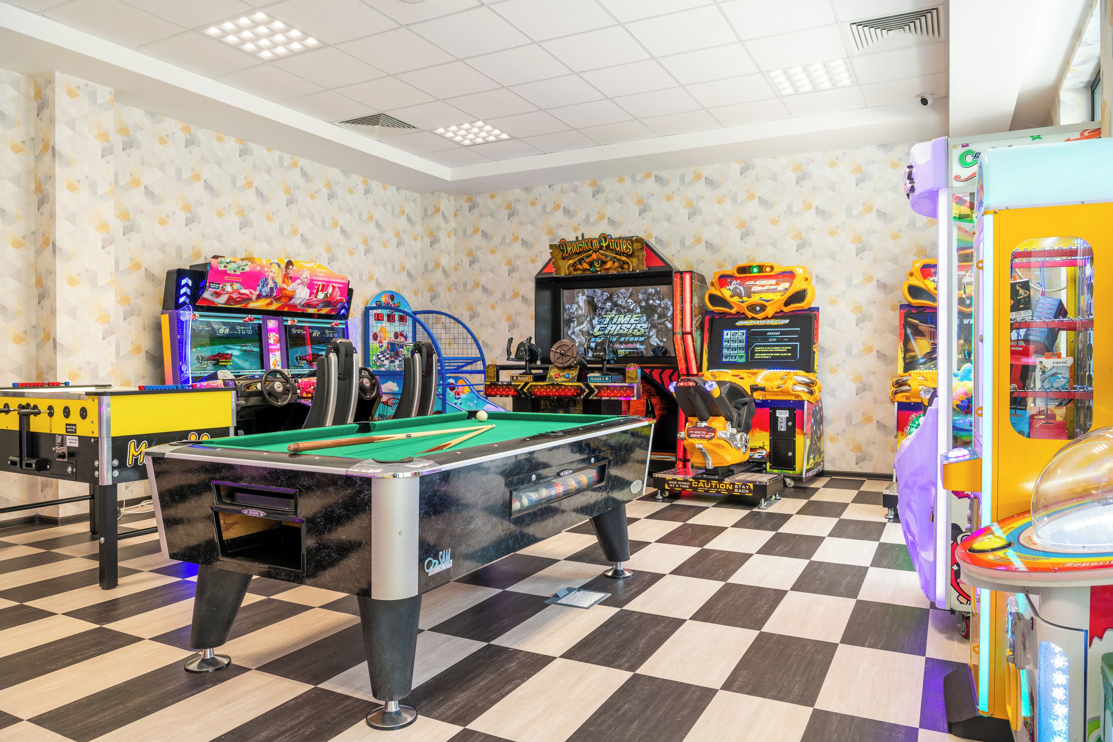 A pool table, arcade machines, and a checkered floor in a recreational area.