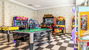 A pool table, arcade machines, and a checkered floor in a recreational area.