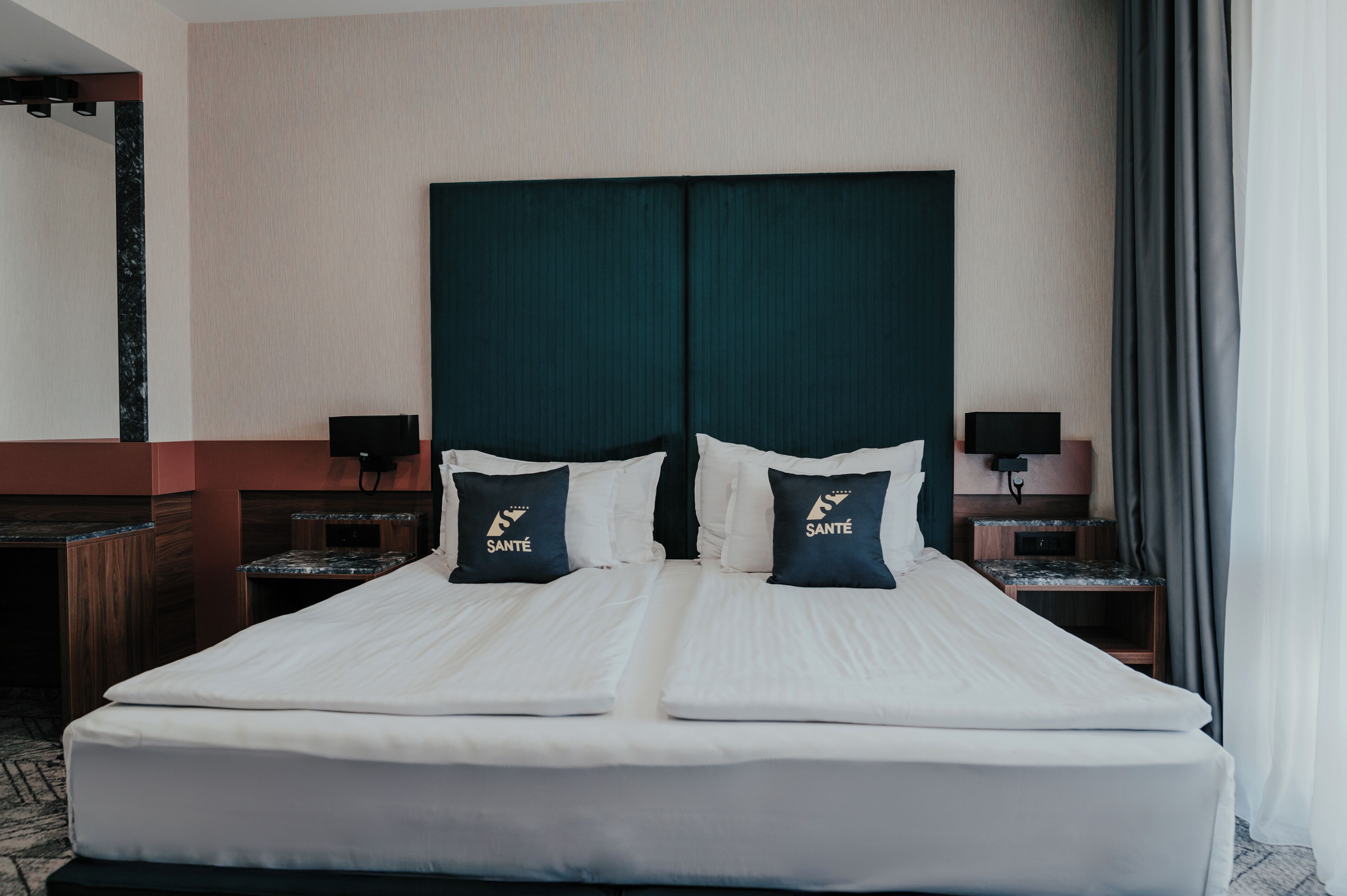 A double bed with two pillows, a nightstand with a lamp, and a wooden bench.