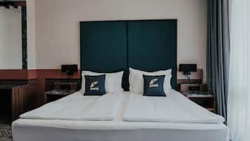 A double bed with two pillows, a nightstand with a lamp, and a wooden bench.
