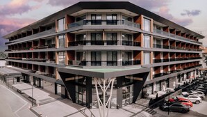 A multi-story hotel with a modern design, featuring balconies, large windows, and a parking area with several cars. - Sante SPA Hotel (Velingrad)