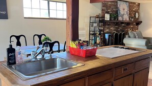 A kitchen with wooden cabinets, a stainless steel sink, and a red basket on the counter.