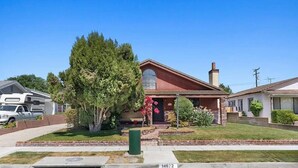A single-story house with a red roof, a chimney, and a front porch.