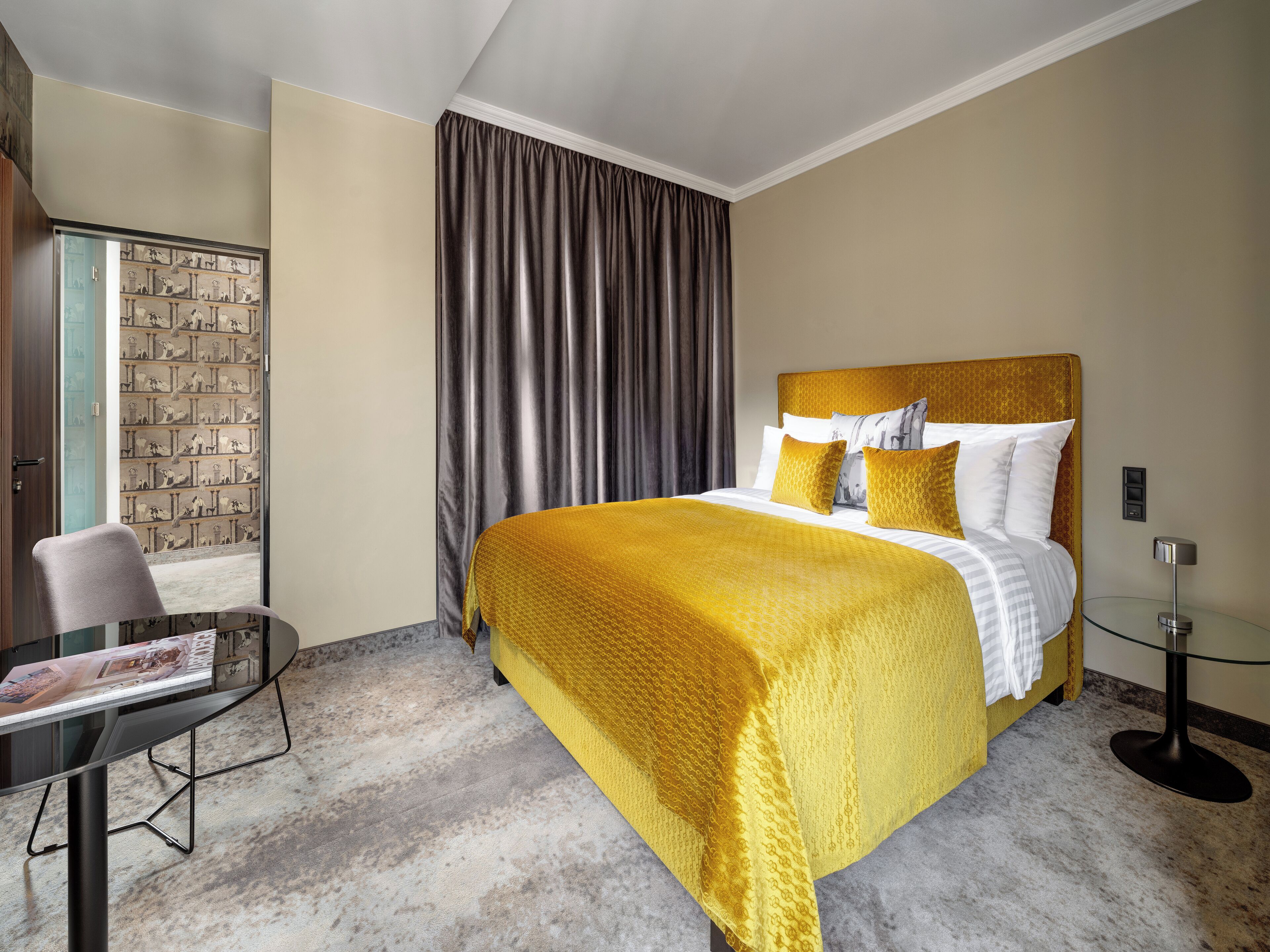 Ein Hotelzimmer mit einem großen Bett, einem Schreibtisch und Blick auf eine Stadtkulisse durch ein mit Vorhängen drapiertes Fenster.