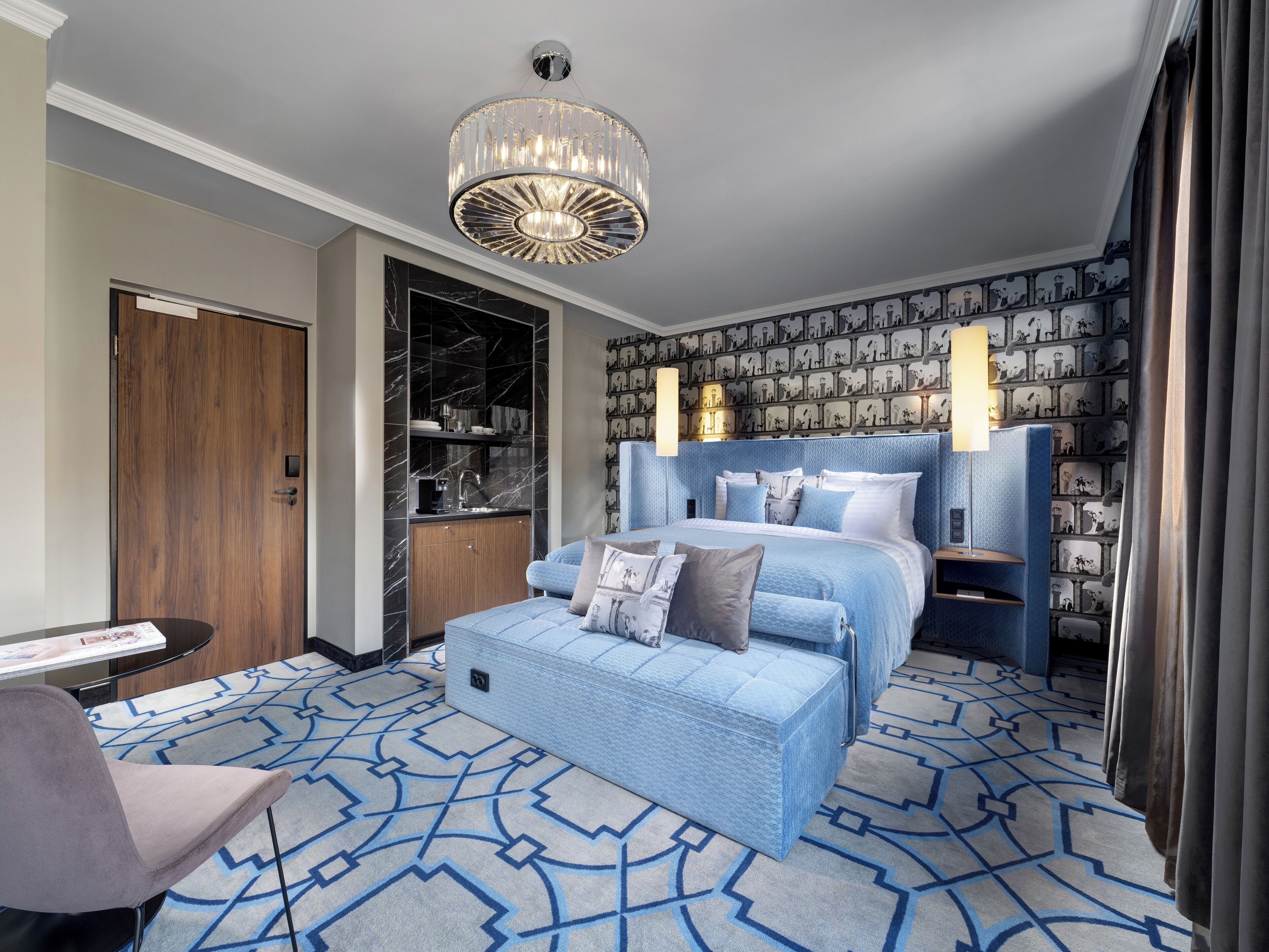 Een moderne hotelkamer met een groot bed, een zithoek, een kledingkast en een badkamer met een marmeren wastafel.
