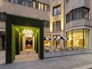 A hotel entrance with a green hedge archway, a chandelier, and outdoor seating. - Mamaison Hotel Chain Bridge Budapest (Budapest)