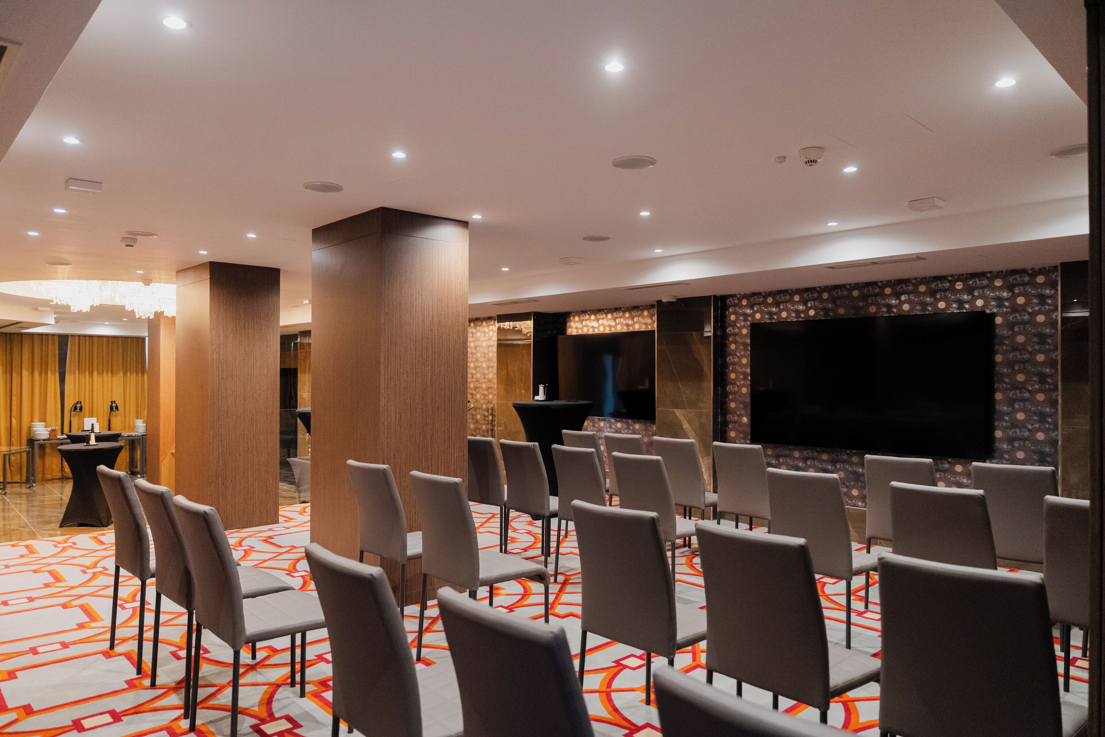 A conference room with rows of chairs, a large screen, and a podium.