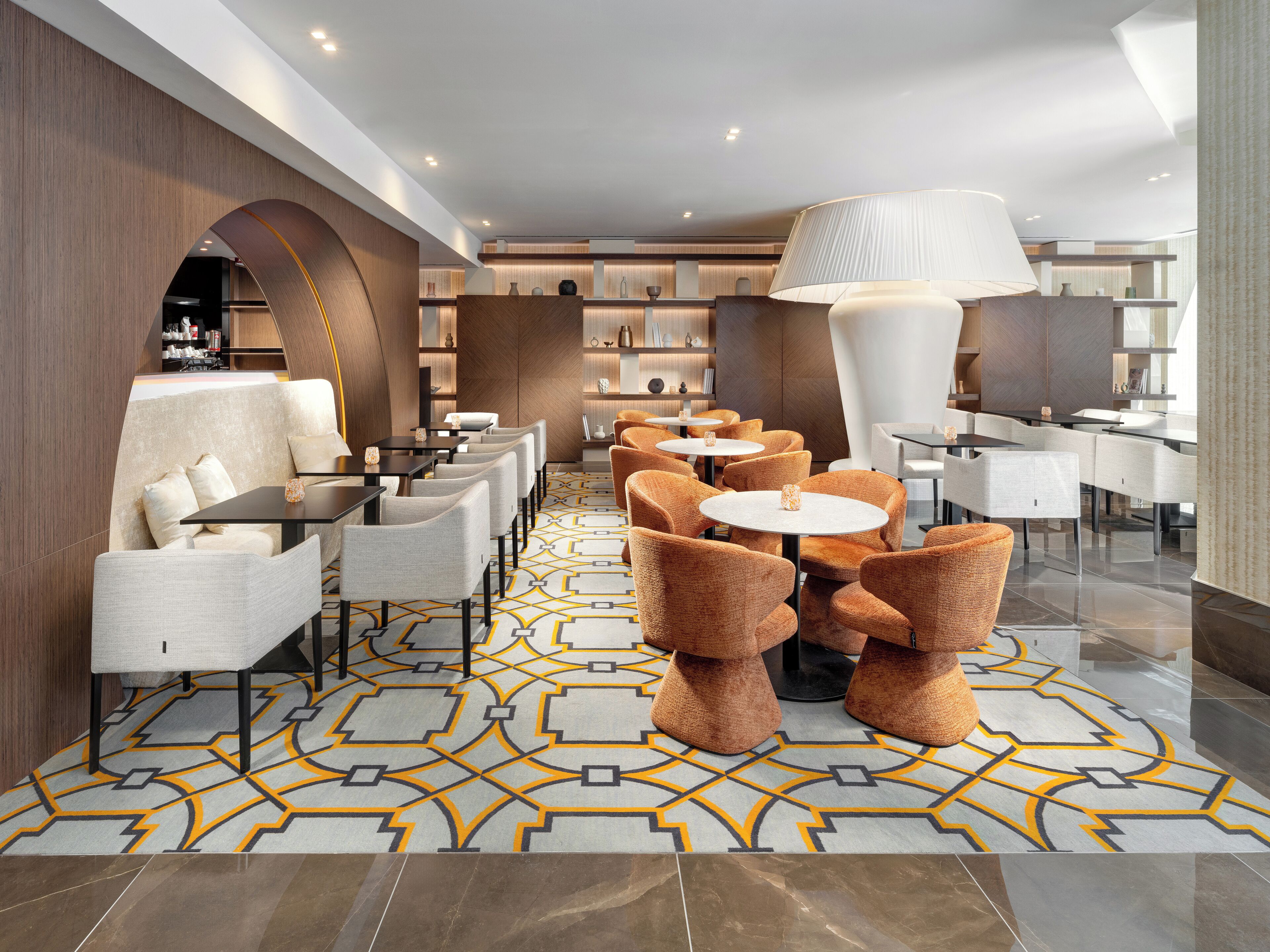A modern lounge area with sofas, armchairs, and round tables.