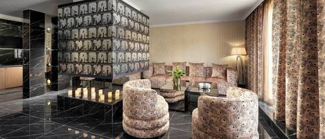 A modern lobby with a marble floor, patterned sofas, and a decorative wall.