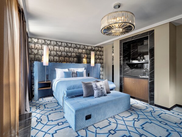 A modern hotel room with a large bed, a wardrobe, and a chandelier.